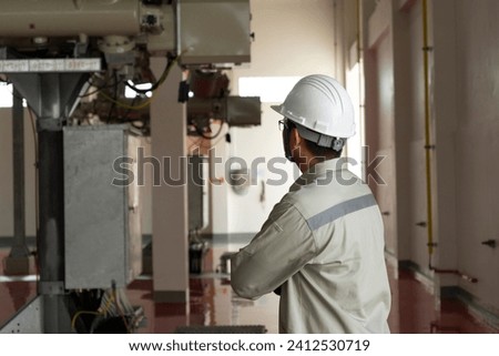 Engineers technicians man wearing professional helmets working in powerhouse interior building. Royalty-Free Stock Photo #2412530719