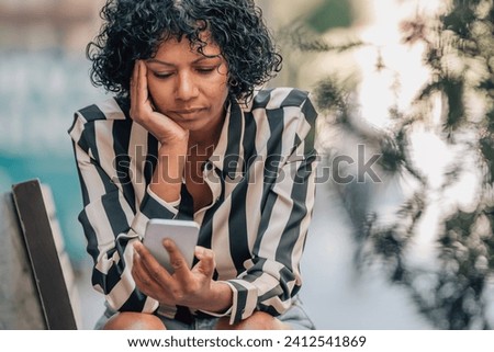 woman on the street sitting with a stressed expression with mobile phone Royalty-Free Stock Photo #2412541869