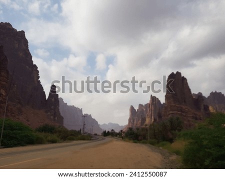 A winding mountain road with towering cliffs , Wadi Disah, Tabouk region, Saudi Ara Royalty-Free Stock Photo #2412550087