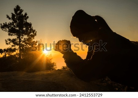 Silhouette of woman kneeling down praying for worship God at sky background. Christians pray to jesus christ for calmness. In morning people got to a quiet place and prayed. copy space. Royalty-Free Stock Photo #2412553729