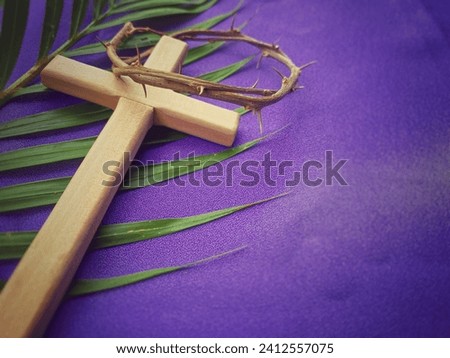 Holy Week, Lent, Palm Sunday, Good Friday, Easter Sunday Concept. Crown of thorns, wooden cross and palm leaf with purple background. Royalty-Free Stock Photo #2412557075