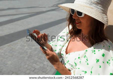Beautiful tourist girl with hat holding mobile phone and talking at the city square.