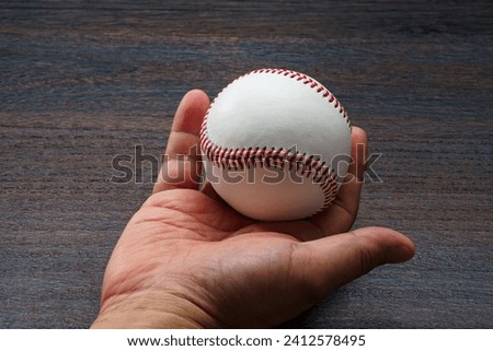 Man's hand holding a baseball ball