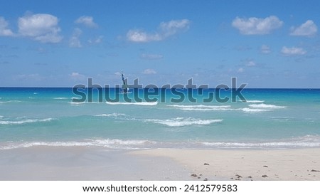 An aerial shot of the blue-wavy ocean at Varadero beach in Cuba with a sailing ship in it