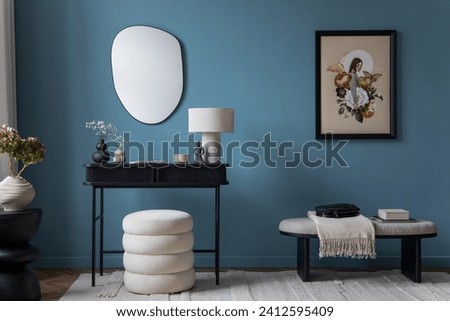 Cozy living room interior with mock up poster frame, white pouf, blue wall, black console, stylish lamp, vase with flowers, wooden stand, bench and personal accessories. Home decor. Template.	 Royalty-Free Stock Photo #2412595409