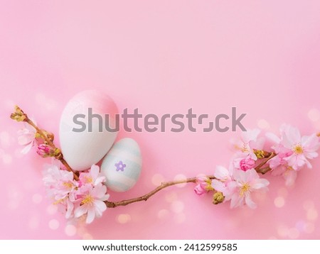 easter eggs and cherry flowers on a pink background with bokeh and copy space.