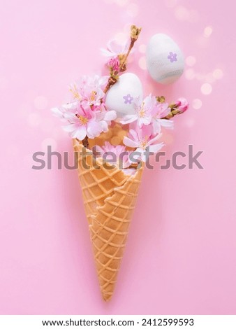 Easter eggs, cherry blossom flowers, waffle cone on a pink background with bokeh and copy space. Vertical creative photo. Church Christian holidays, Christianity, Easter background.
