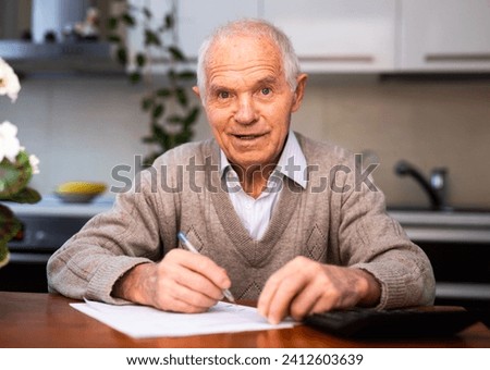 Old gray haired man sits at table Royalty-Free Stock Photo #2412603639
