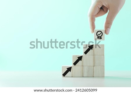 Hand-putting a symbol of quality assurance and arrow increasing on wooden cube for quality enhancement of guarantee product and ISO service concept. Enhance the value of business. Proposal compliance,