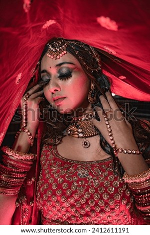 Delhi, India - December 5th 2022 - Pictures of a beautiful Indian woman in a red bridal lehenga with gold jewelry for woman, necklace, earrings and bangles.
