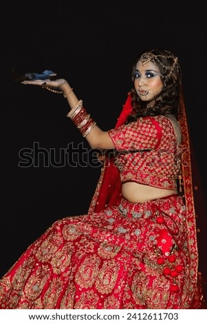 Delhi, India - December 5th 2022 - Pictures of a beautiful Indian woman in a red bridal lehenga with gold jewelry for woman, necklace, earrings and bangles.