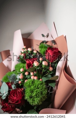 The bouquet of fresh flowers including red roses, berries, dianthus green balls