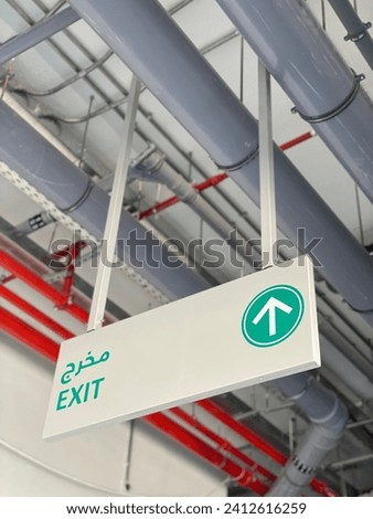 A suspended panel in the ceiling indicates the direction of the exit from the parking lots and it is written in Arabic and English