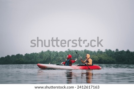 Kerala tourism concept photo two guys kayaking in a lake, shot from Kavvayi Island Kannur, Kerala backwaters adventure image Royalty-Free Stock Photo #2412617163