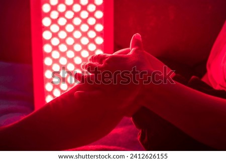 Closeup of sore leg of a person treating with the red light therapy panel Royalty-Free Stock Photo #2412626155