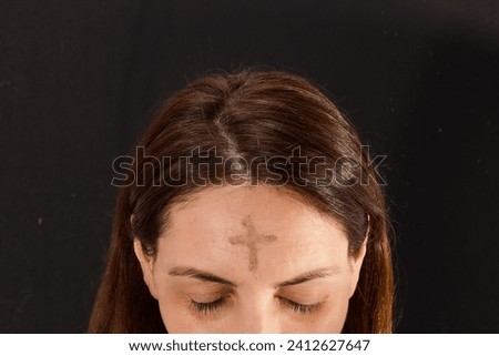 Woman with cross made from ash on forehead. Ash wednesday concept. Royalty-Free Stock Photo #2412627647