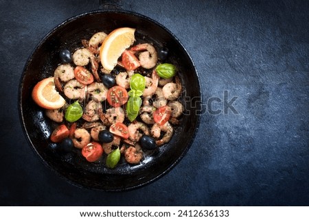 Fried tiger shrimps with ingredients in the pan from above on dark background with blank space Royalty-Free Stock Photo #2412636133