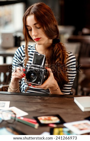 Young woman photographer with old 6x6 frame camera sitting in the cafe