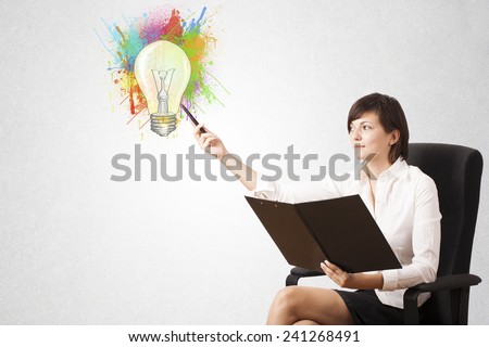 Young lady drawing a colorful light bulb with colorful splashes on white background