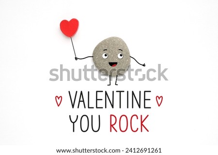 Funny cute stone and text Valentine you rock. Cool encouragement concept. Realistic stone with painted arms, legs and face. Royalty-Free Stock Photo #2412691261