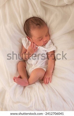 Cute little sleeping African biracial newborn baby sleeping in a simple white romper Royalty-Free Stock Photo #2412706041
