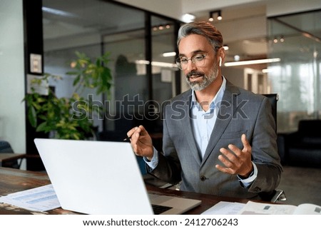 Middle-age Hispanic man using computer remote for business studying, watch online virtual webinar training meeting, video call. Smiling mature Indian or Latin businessman working on laptop in office. Royalty-Free Stock Photo #2412706243