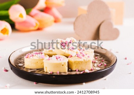 White chocolate candies in the shape of a heart with icing on a plate