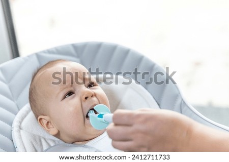 Newborn baby suffering of his tooth growth, mom using a teether to ease the pain, healthcare concept