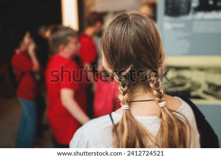 Group of students and school pupils in a science museum exhibition, excursion tour with guide, a docent with a tourist visitors, school field trip, attendees of technical museum exposition gallery Royalty-Free Stock Photo #2412724521