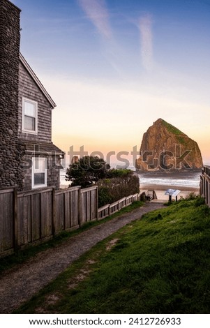 A fine art landscape photography image of Cannon Beach Haystack framed along a lush and green pathway leading to the coastline