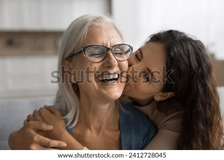Happy loving adult daughter kissing cheerful laughing mature mum with love, gratitude, congratulating on mothers day, enjoying family meeting, visit, friendship, leisure time Royalty-Free Stock Photo #2412728045