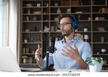 Man wear headphones talk into microphone participate in stream event. Young businessman in glasses sit at office use laptop take part in online negotiation, lead business meeting. Tuition, training