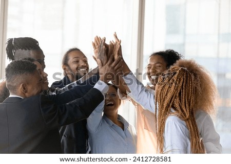Corporate spirit. Diverse team of young active employees unite hands in high five. Excited motivated ethnic businesspeople group celebrate success as great result of collaborative teamwork Royalty-Free Stock Photo #2412728581