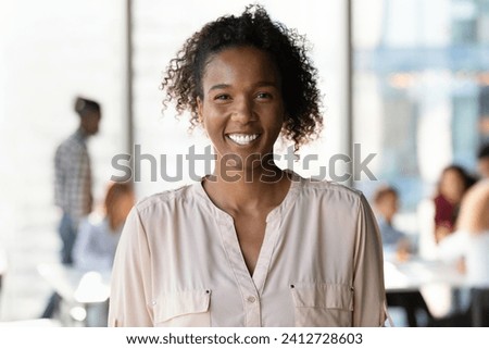Modern youth representative. Headshot portrait of happy smiling millennial mixed race woman employee student posing in office university. Casual young black female teenager look at camera in good mood Royalty-Free Stock Photo #2412728603