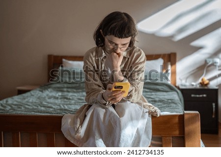 Nervous, stressed teen girl in glasses reading messages in smartphone feeling bad, humiliated. Depressed frustrated woman receive negative message in social media from haters. Cyberbullying, stalking. Royalty-Free Stock Photo #2412734135