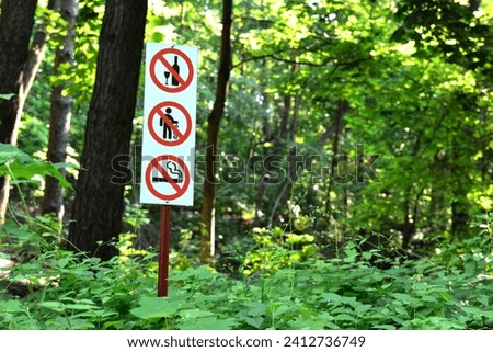 A wooden pole with prohibition signs in a park or forest. a safe public space in the green zone of the city.
