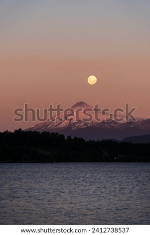 Amazing view of a volcano iluminated by a full moon during the sunset in the lake