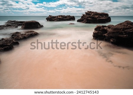 Stones in the water wih long exposure photography in a cave beach of Australia.