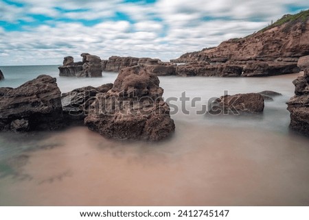 Stones in the water wih long exposure photography in a cave beach of Australia.
