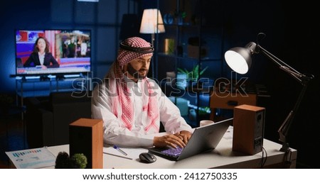 Muslim man at home paying attention in elearning seminar teleconference with teacher, writing on notepad. Middle Eastern homeschooling student listening to lesson while doing his homework tasks