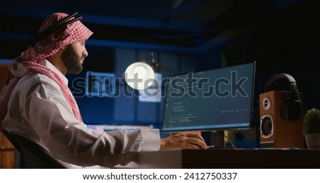 Arab technician writing script code on computer screen inputting commands on terminal. Middle Eastern teleworking employee at home working on fixing company internal database errors