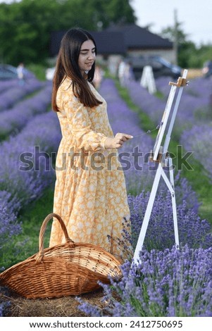 Portrait of a brunette woman in yellow dress painting picture in the lavender field.