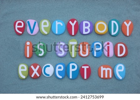 Everybody is stupid except me, self satisfaction quote composed with multi colored stone letters over green sand