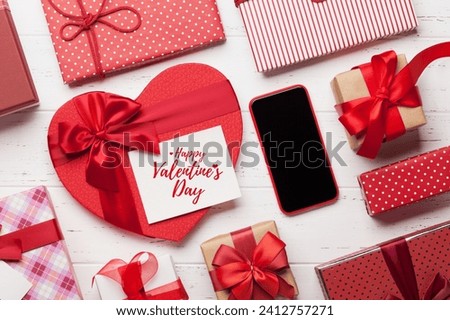 valentine's day greeting card with gift boxes and smartphone on wooden background Royalty-Free Stock Photo #2412757271