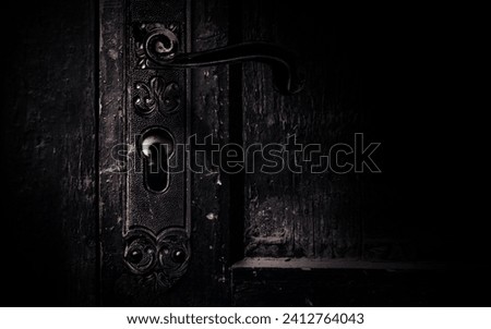 Photo of old obsoltete and shaded abandoned grungy door handle with horror scary eye peaking from keyhole. Royalty-Free Stock Photo #2412764043