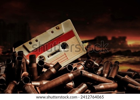 Photo of an old audio tape cassette on pile of bullets. Ruined city battlefied or wasteland background.