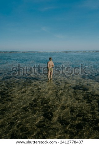 Girl in bikini against infinite blue sea and sky background.