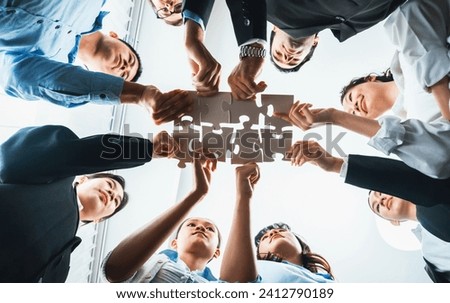 Multiethnic business people holding jigsaw pieces and merge them together as effective solution solving teamwork, shared vision and common goal combining diverse talent. Below view. Habiliment Royalty-Free Stock Photo #2412790189