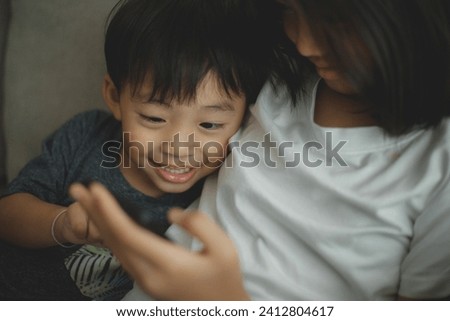 Little girls and boy siblings look at the phone and smile. They hold a smartphone watch videos, learn, play games, and speak online. Internet for children. Parental control