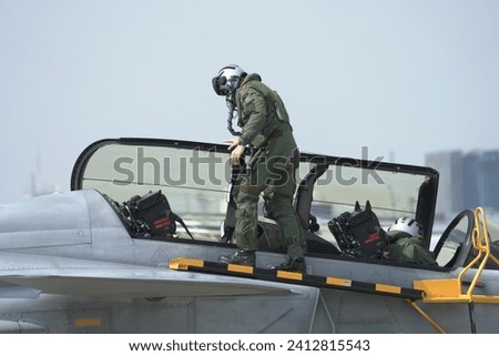 A pilot and co pilot in a G-suit inspects a fighter jet. Control panel area on the side of the aircraft fuselage. Check readiness before flying. Royalty-Free Stock Photo #2412815543